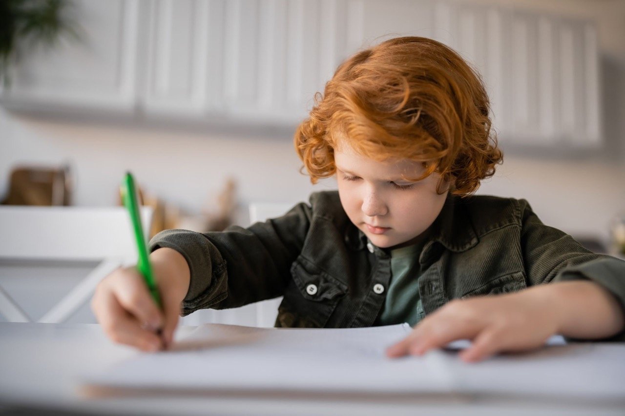 Bambino che scrive con una matita, immagine dedicata alla disgrafia nei bambini e alle difficoltà di scrittura - Develop Players